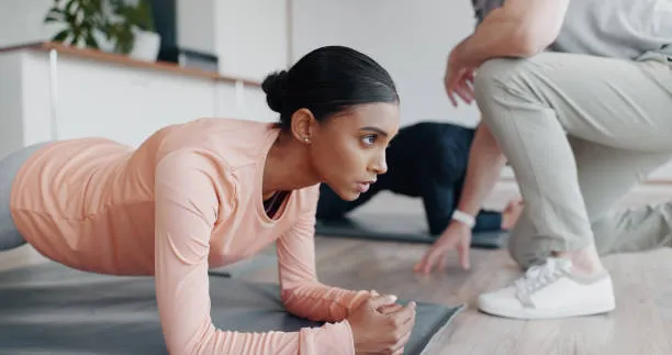 Patient holding a plank while a therapist coaches form